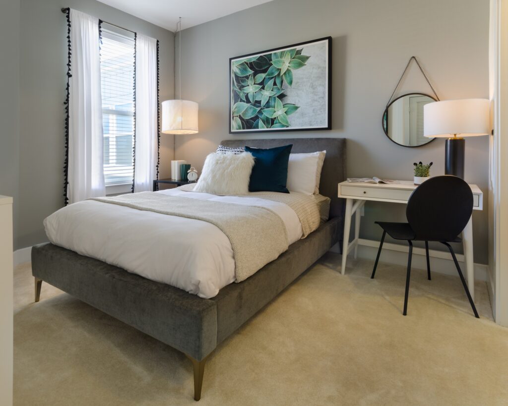 staged bedroom with large window and light gray accent wall