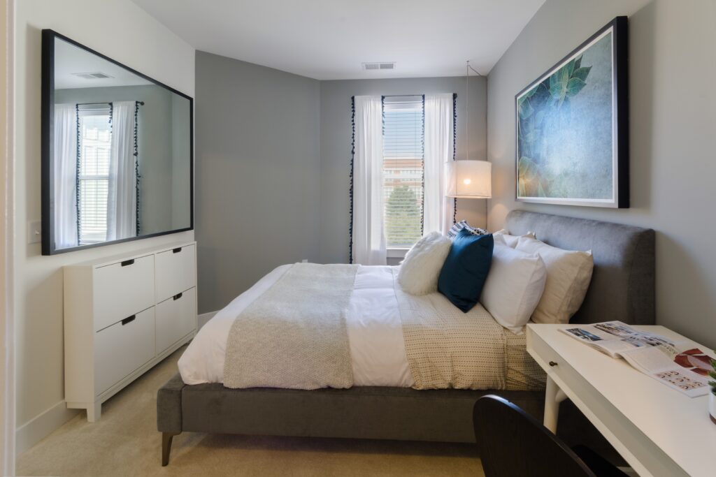 Staged bedroom with light gray accent wall and large window