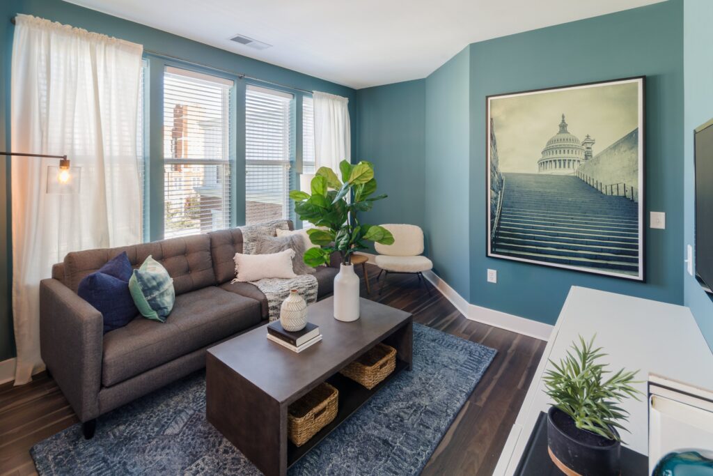 staged living room with large windows and blue walls